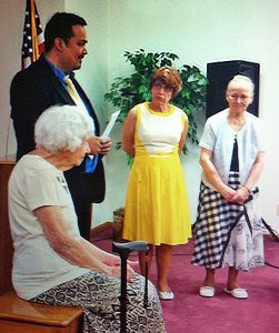 Pastor Joe Arellano welcomes Hope Hellige (seated), Sandy McCollum (in yellow) and Mildred Rempe into the Ft. Madison Adventist Church on profession of faith. Photo by Harry Scanlan.