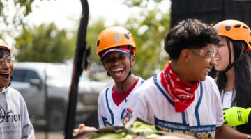 Pathfinders smile as they bring their mannequin victim on a stretcher.